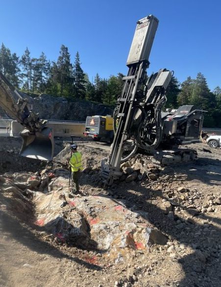 Surveyor beside a drilling rig at a rock excavation
