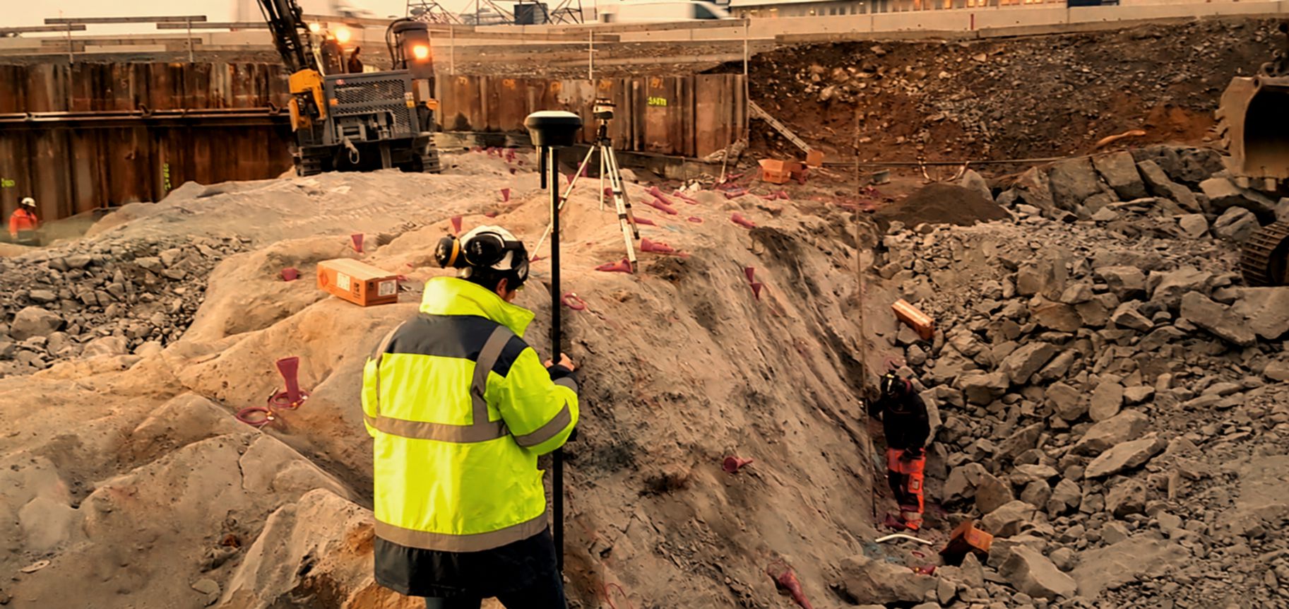 Surveyor using a GNSS rod in a rock excavation