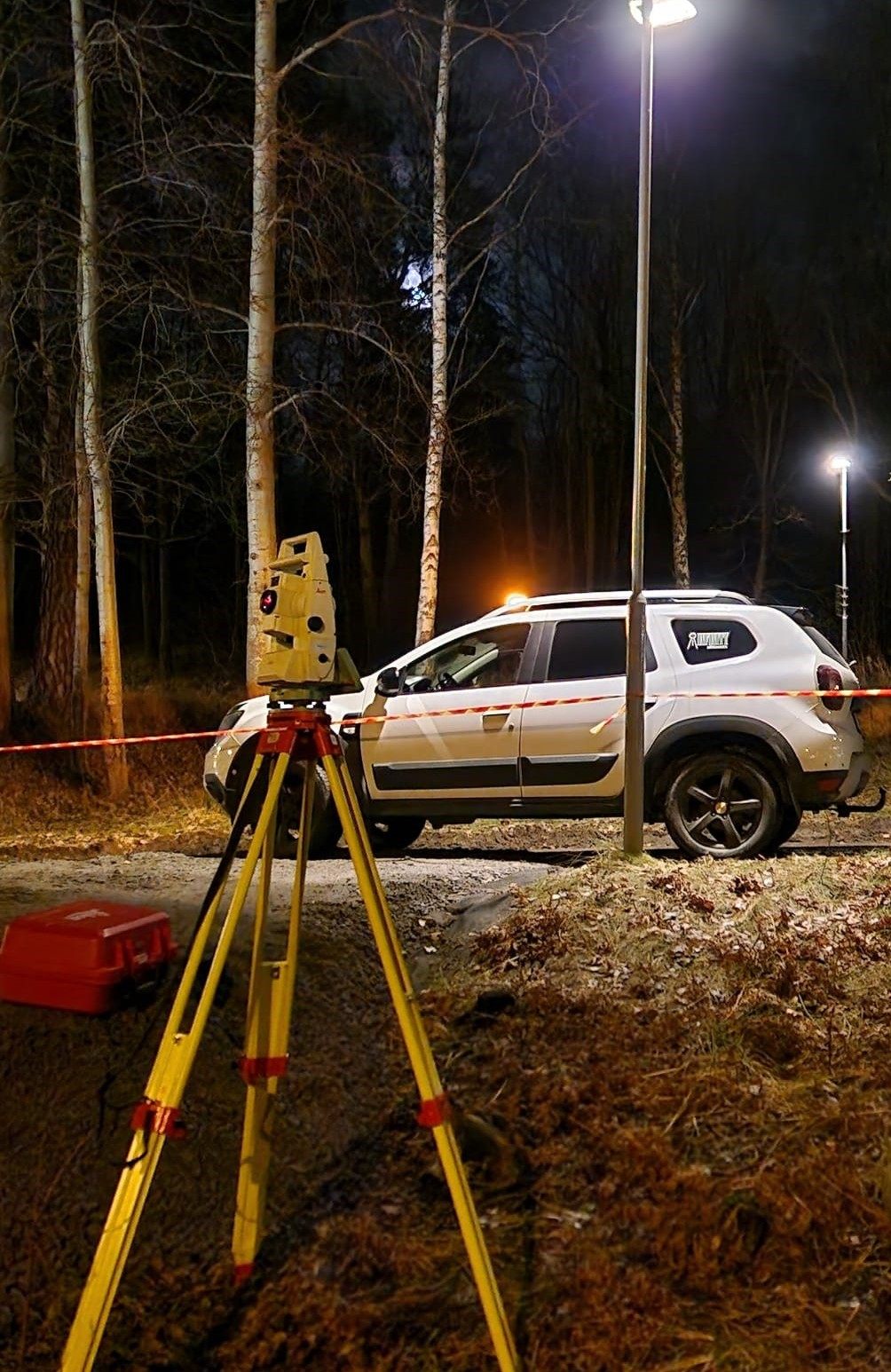 Total station set up beside a vehicle at night